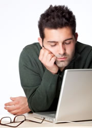 a tired looking man looking at a laptop computer