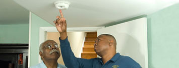 Photo: A man demonstrating how to test a smoke alarm.