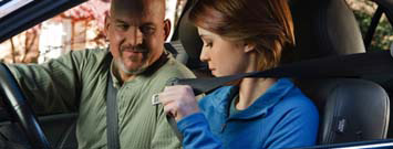 Photo: A young driver putting on a seatbelt.