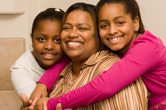 Two daughters hug their mom.
