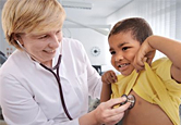 A doctor listens to a young boy's heart.