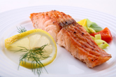 A baked piece of salmon is served with veggies.