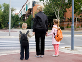 A mom holds her son and daughter's hands.
