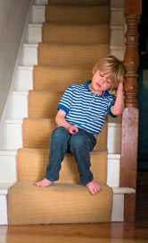 A sad boy sits on the stairs.