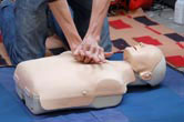 A person practices CPR on a doll.