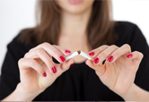 A woman breaks a cigarette in half.