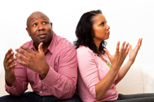 Photo of a man of and woman throwing their hands up in frustration at each other.